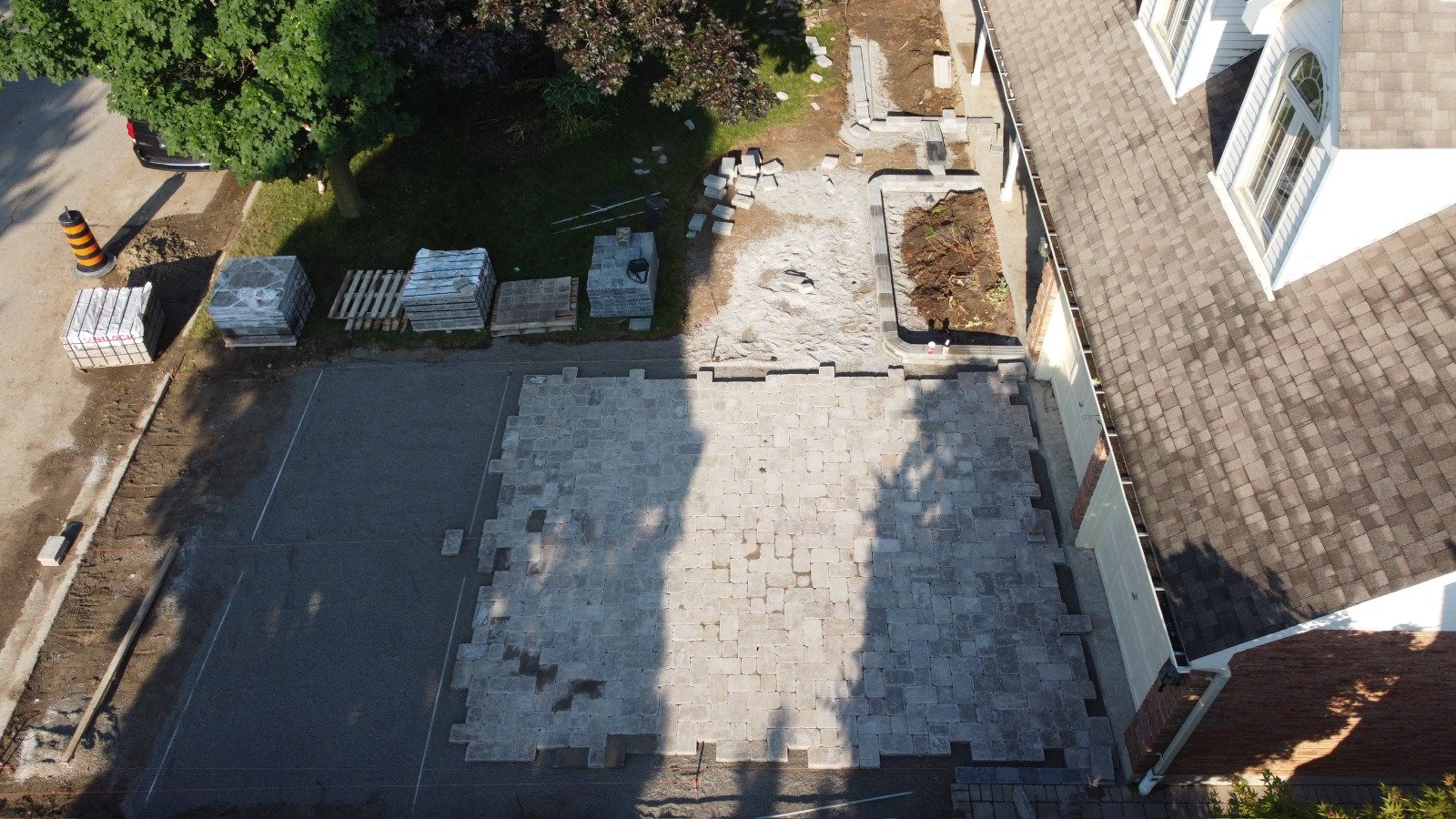 Aerial view of an interlock patio being laid beside a house