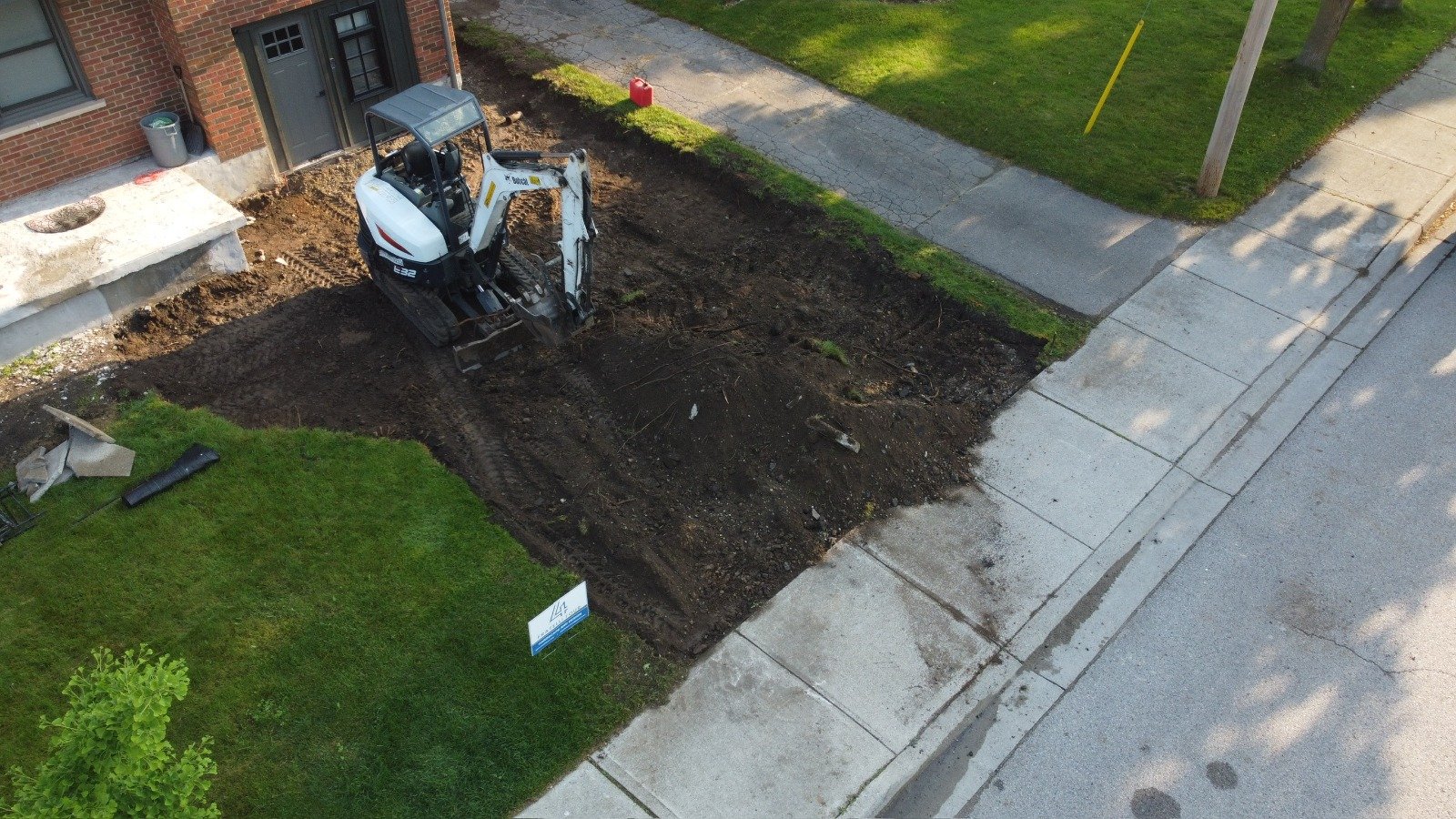 Aerial view of a mini excavator digging out a front yard